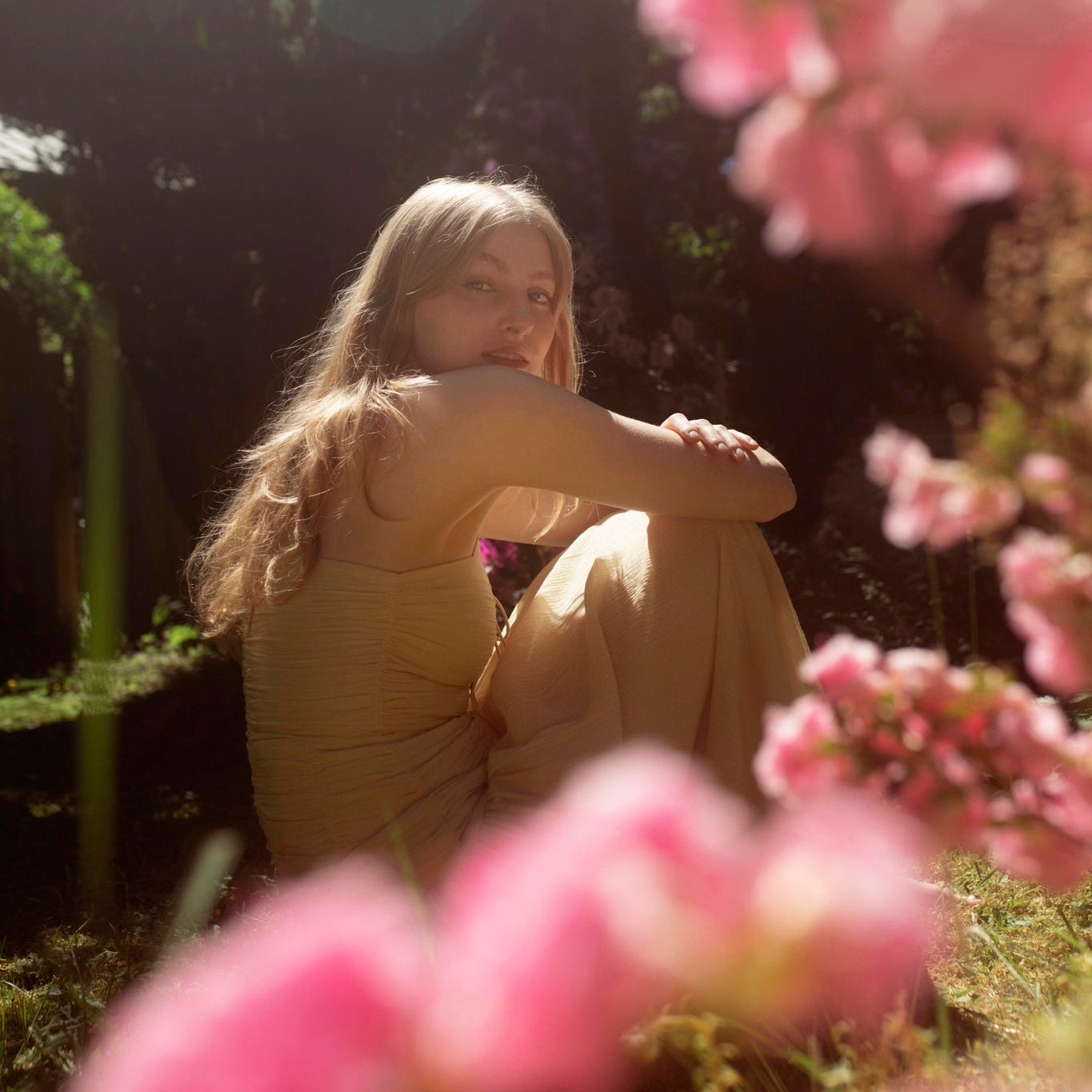 Woman sitting in a garden with pink flowers in the foreground