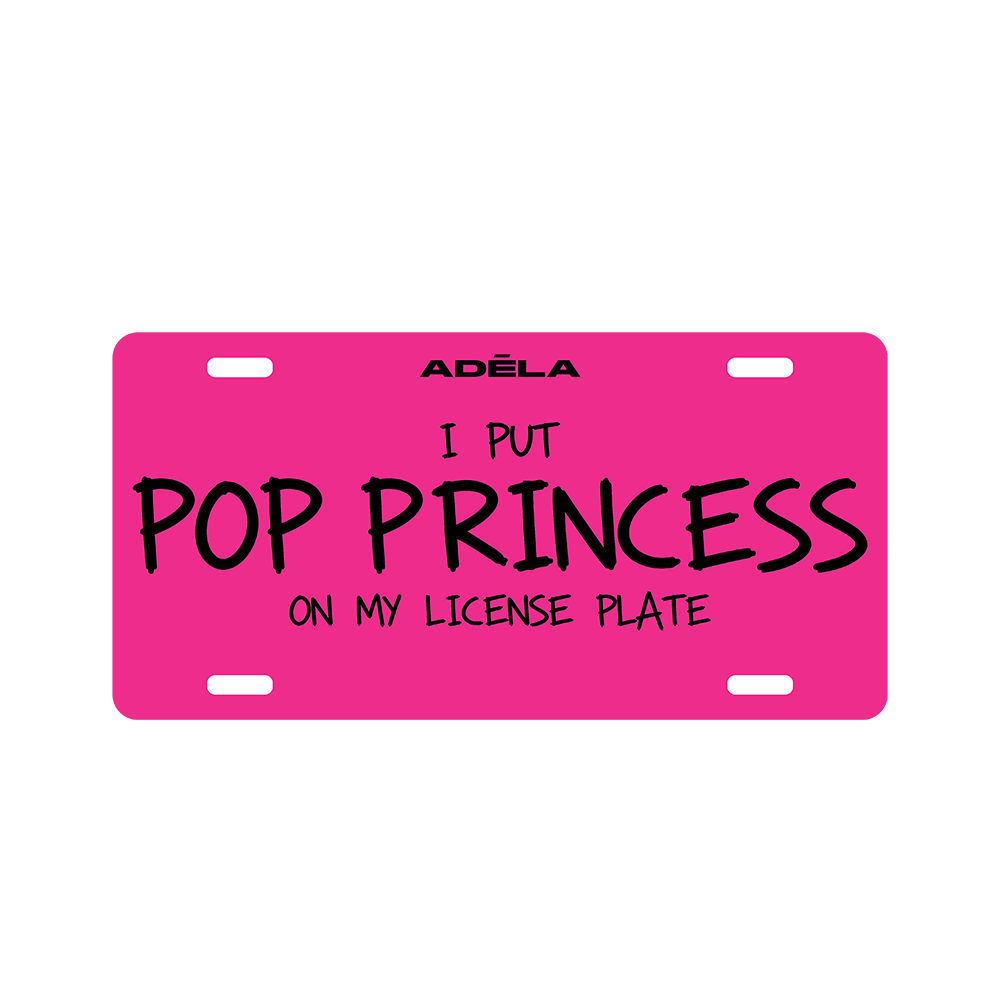 A bright pink novelty license plate with black text reading 'I PUT POP PRINCESS ON MY LICENSE PLATE' and the brand name 'ADĀLA' at the top, shown on a plain white background.