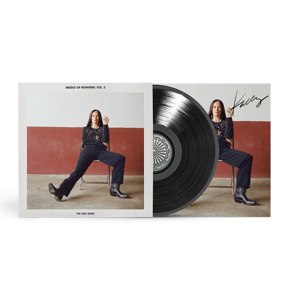 A vinyl record album shown open to reveal a black record alongside the printed cover art. The cover features a seated woman against a red-and-white wall, with the title 'Middle of Nowhere Vol.