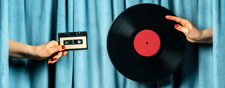 Hands holding a cassette tape and vinyl record against a blue curtain background